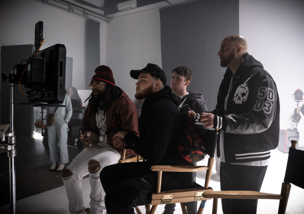 Music video producers Sebastian Santiago and Adam Geiser sit with rapper Money Man and EMPIRE record label owner Ghazi Sham at the video set for Money Man's song "Drums."